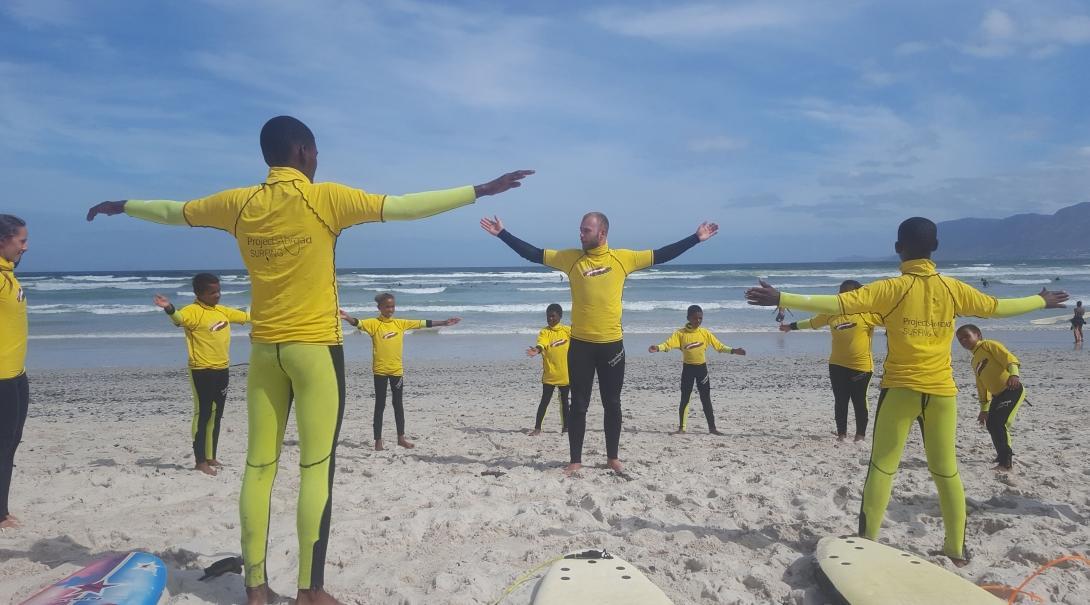 Children learn surfing techniques from a group of Global Gap Year volunteers in South Africa. Global Gap volunteers teach children surfing techniques before going into the water at a beach in South Africa.